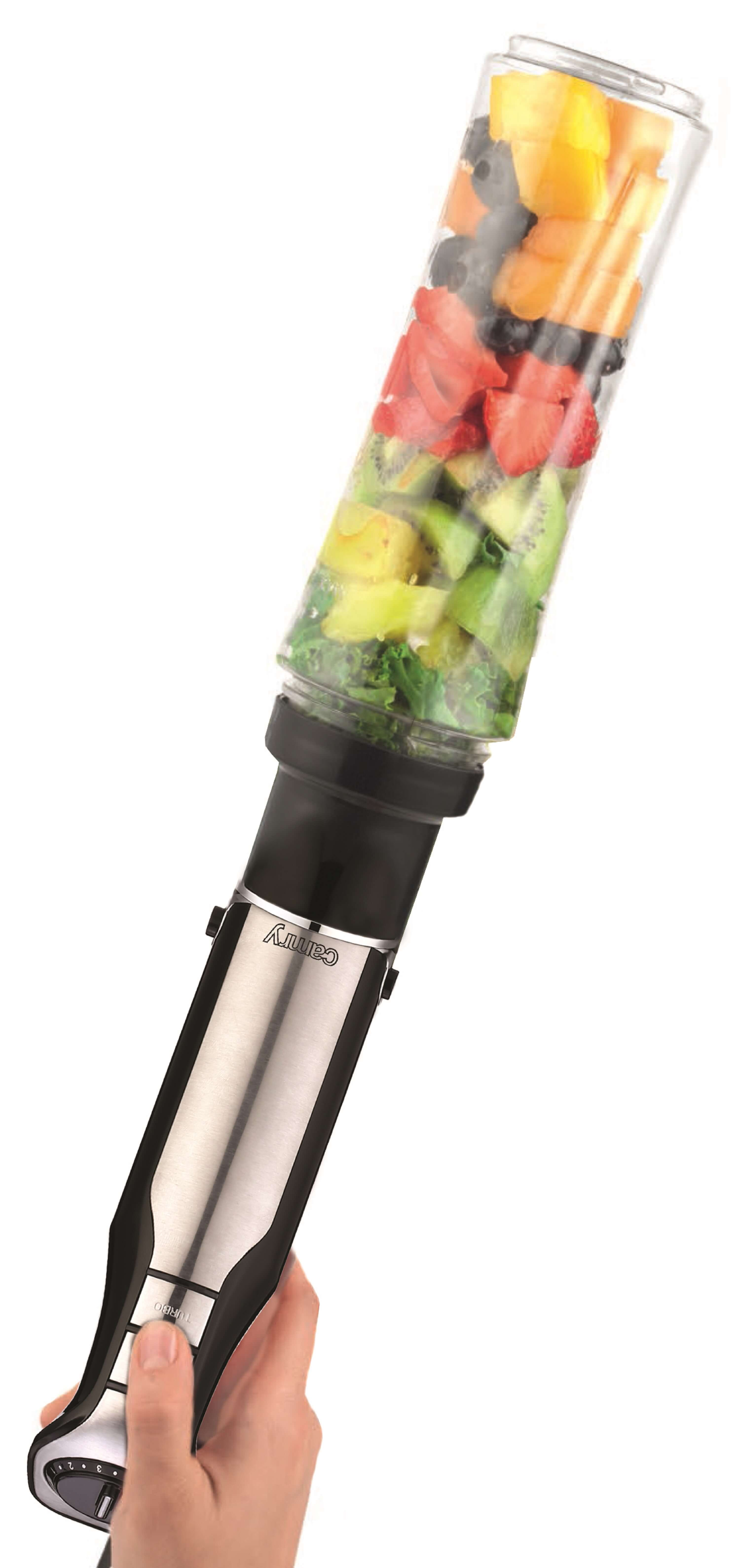 Ręka trzymająca srebrno-czarny blender ręczny z pojemnikiem wypełnionym owocami.