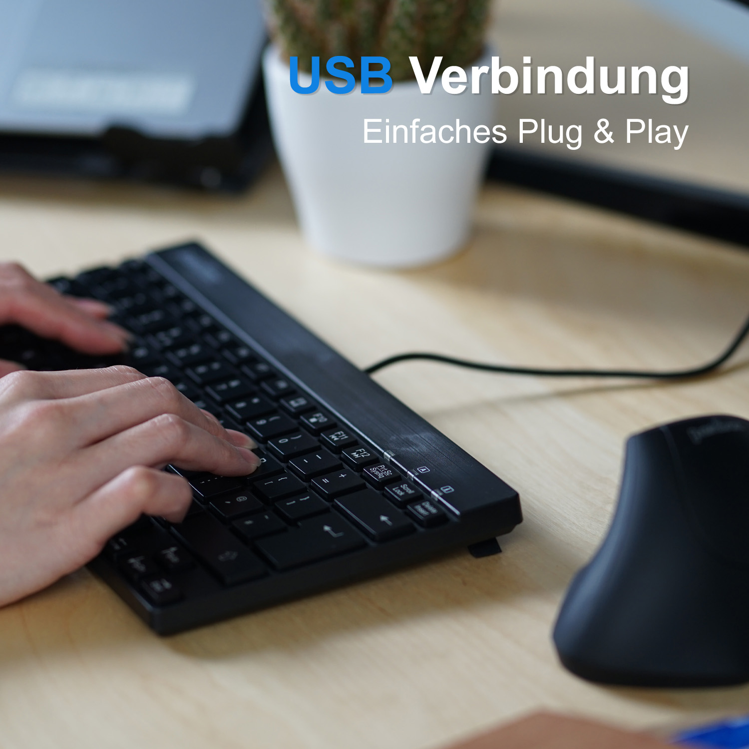 Hände, die auf einer schwarzen Tastatur mit einer schwarzen Maus auf einem Schreibtisch tippen, mit Text.