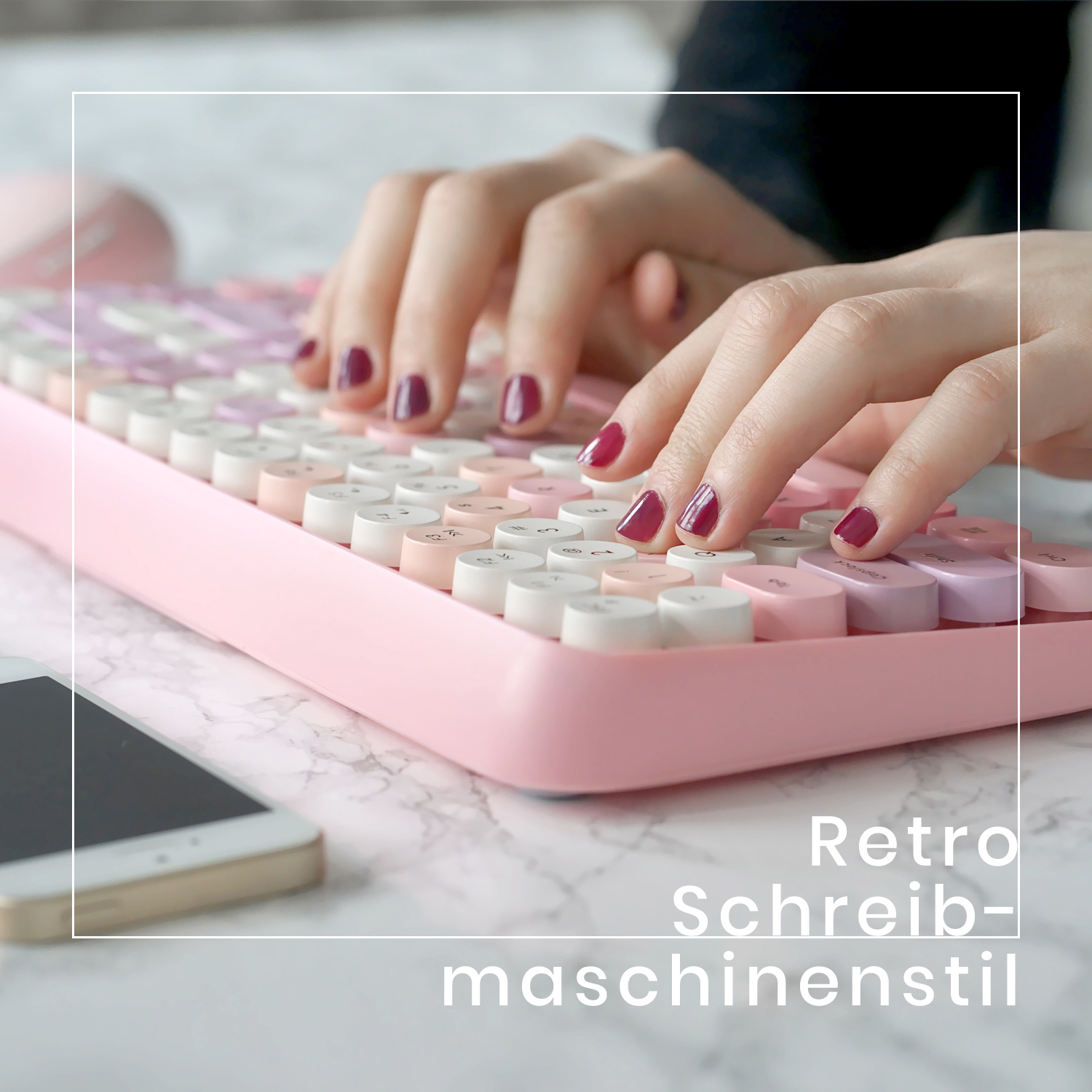 Hände auf einer pinkfarbenen Retro-Schreibmaschinen-Tastatur mit Handy daneben.