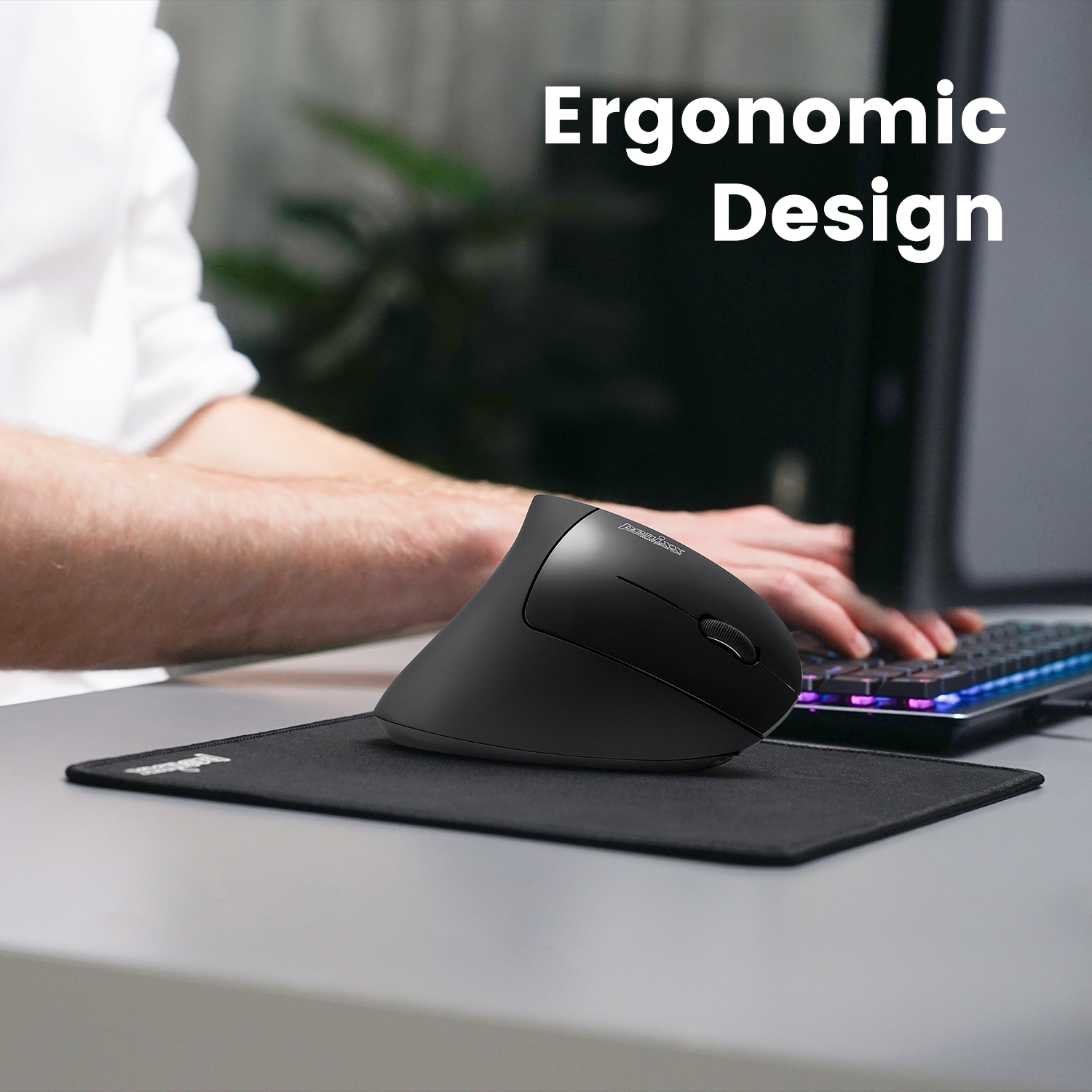 Czarna ergonomiczna mysz na czarnej podkładce. Ręce osoby znajdują się w pobliżu klawiatury.