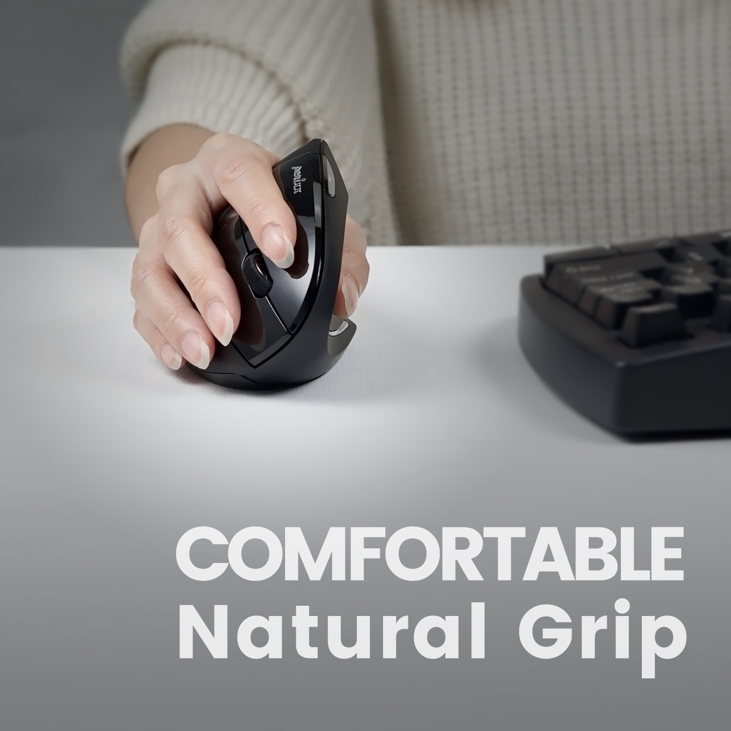 Dłoń trzymająca czarną mysz pionową na białym biurku. Klawiatura w tle.