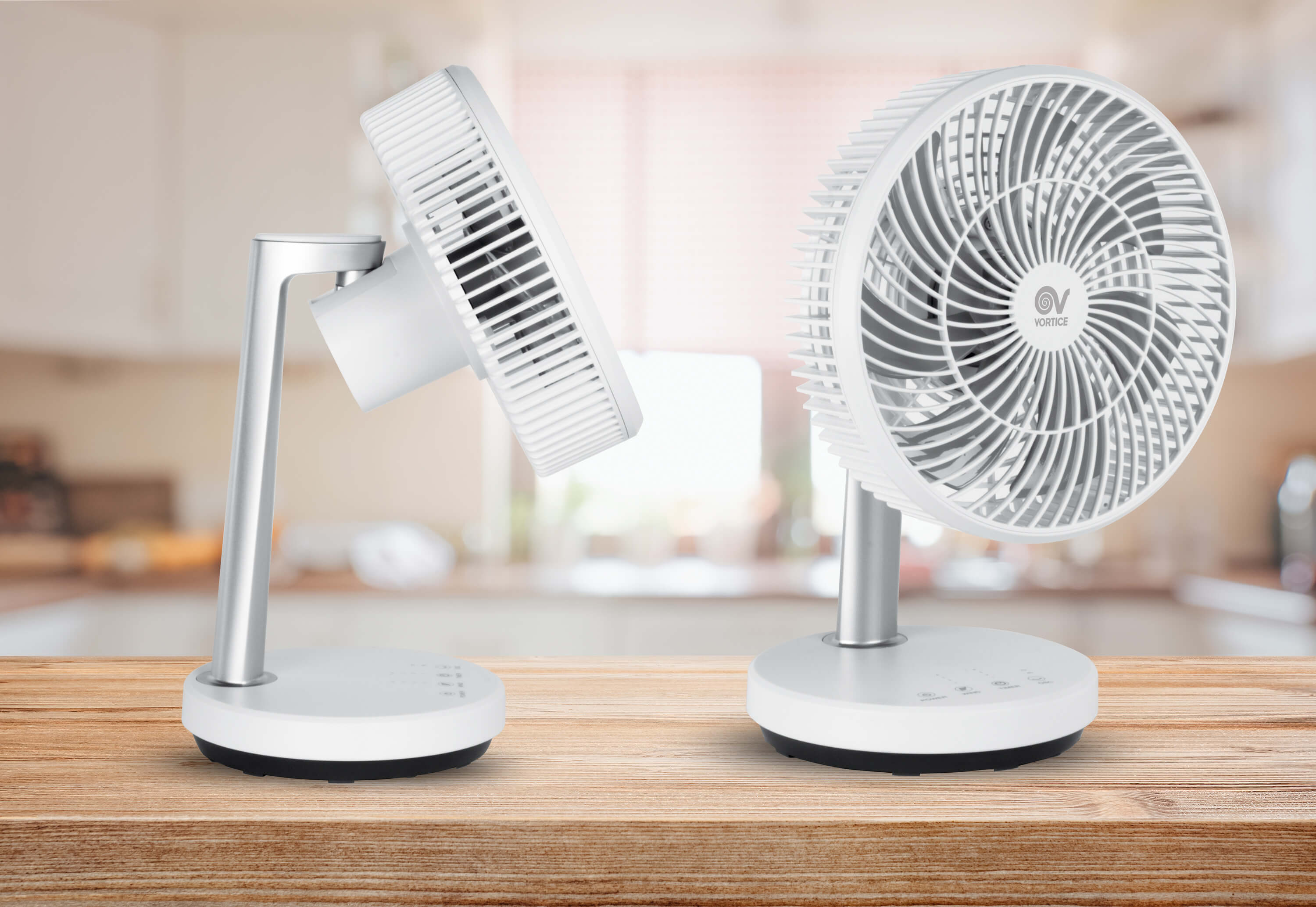 Zwei weiße Ventilatoren auf Holztisch, einer geneigt. Küche im Hintergrund.