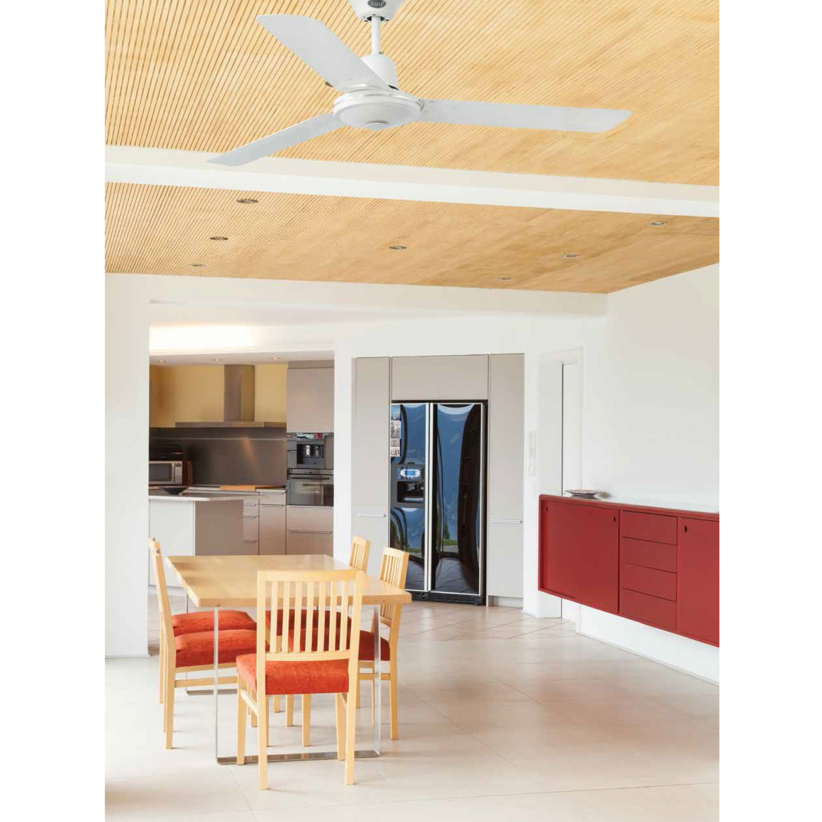 Cucina con ventilatore a soffitto, tavolo con sedie e armadi rossi. Interni luminosi e moderni.