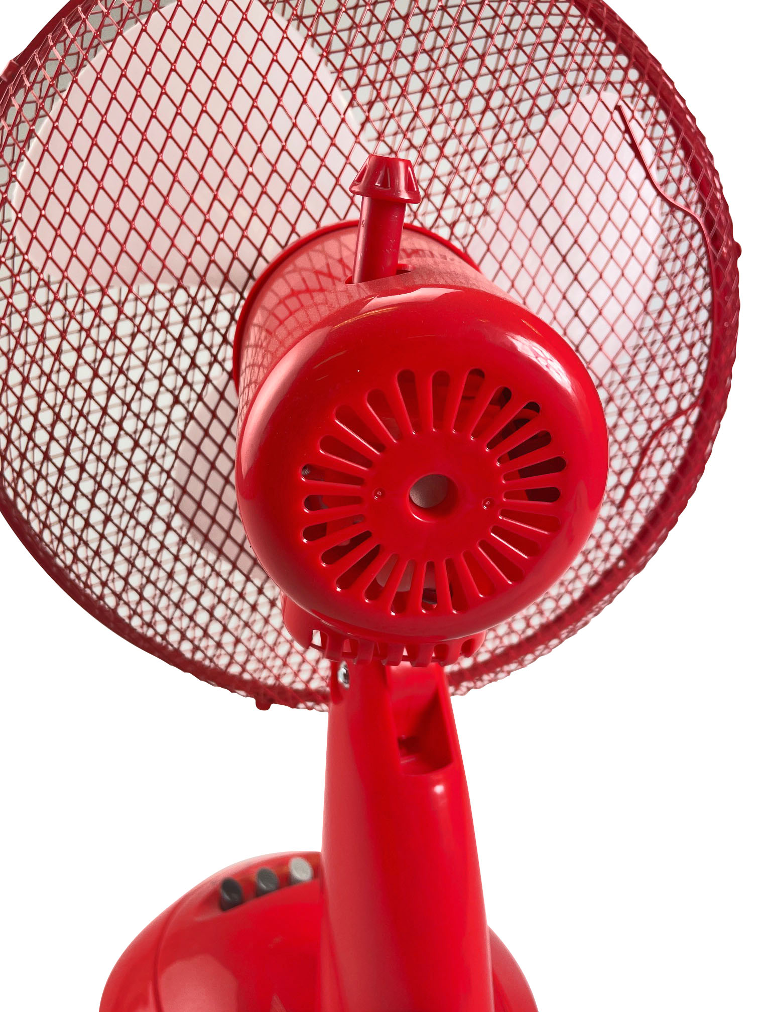 Czerwony wentylator biurkowy, zbliżenie. Wentylator jest włączony.