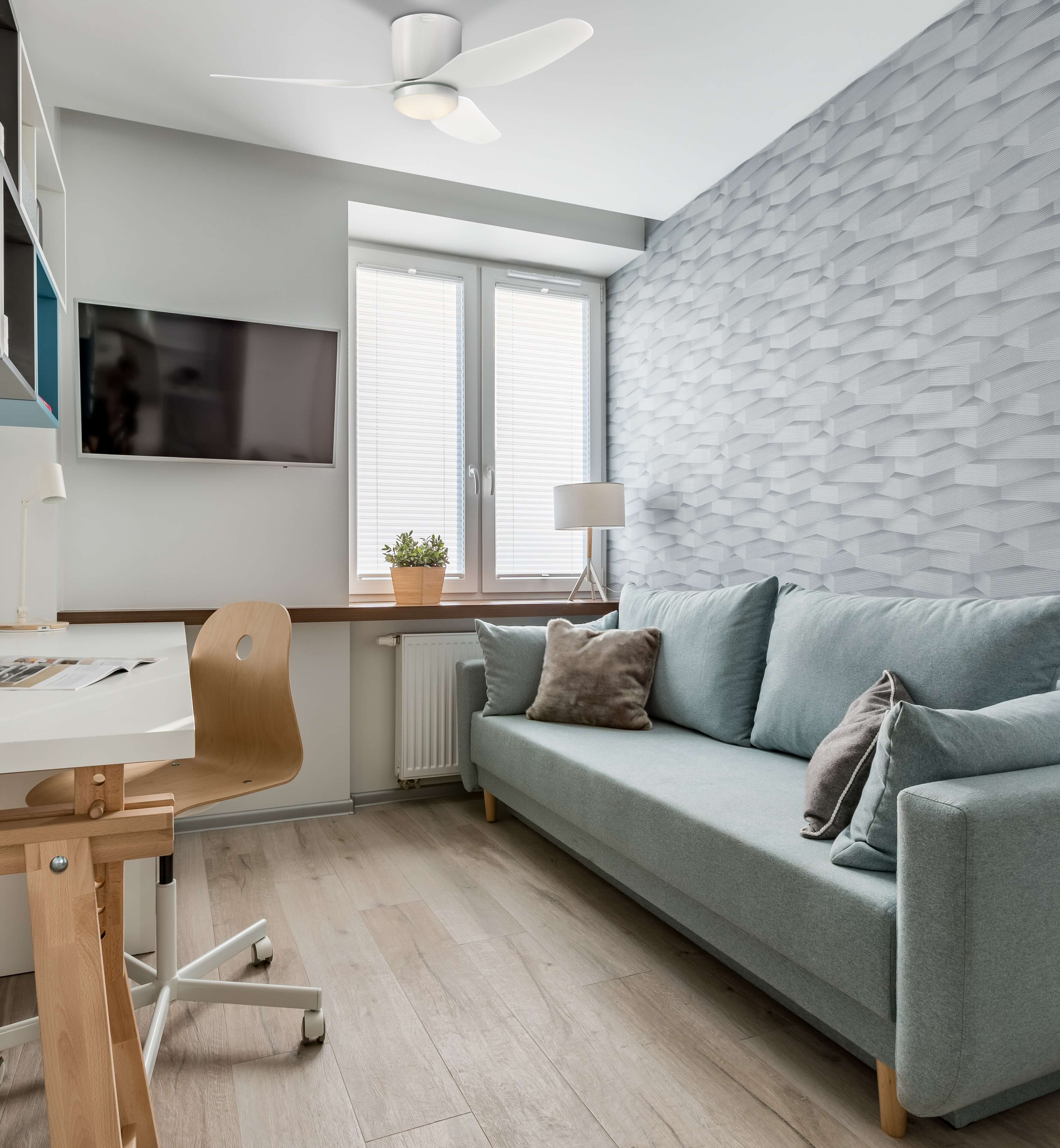 Wohnzimmer mit Sofa, Fernseher und Deckenventilator.