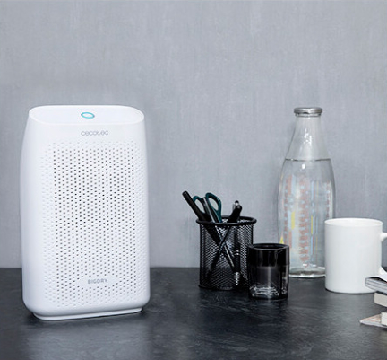 Biały osuszacz na biurku z butelką wody, kubkiem i pojemnikiem na długopisy.