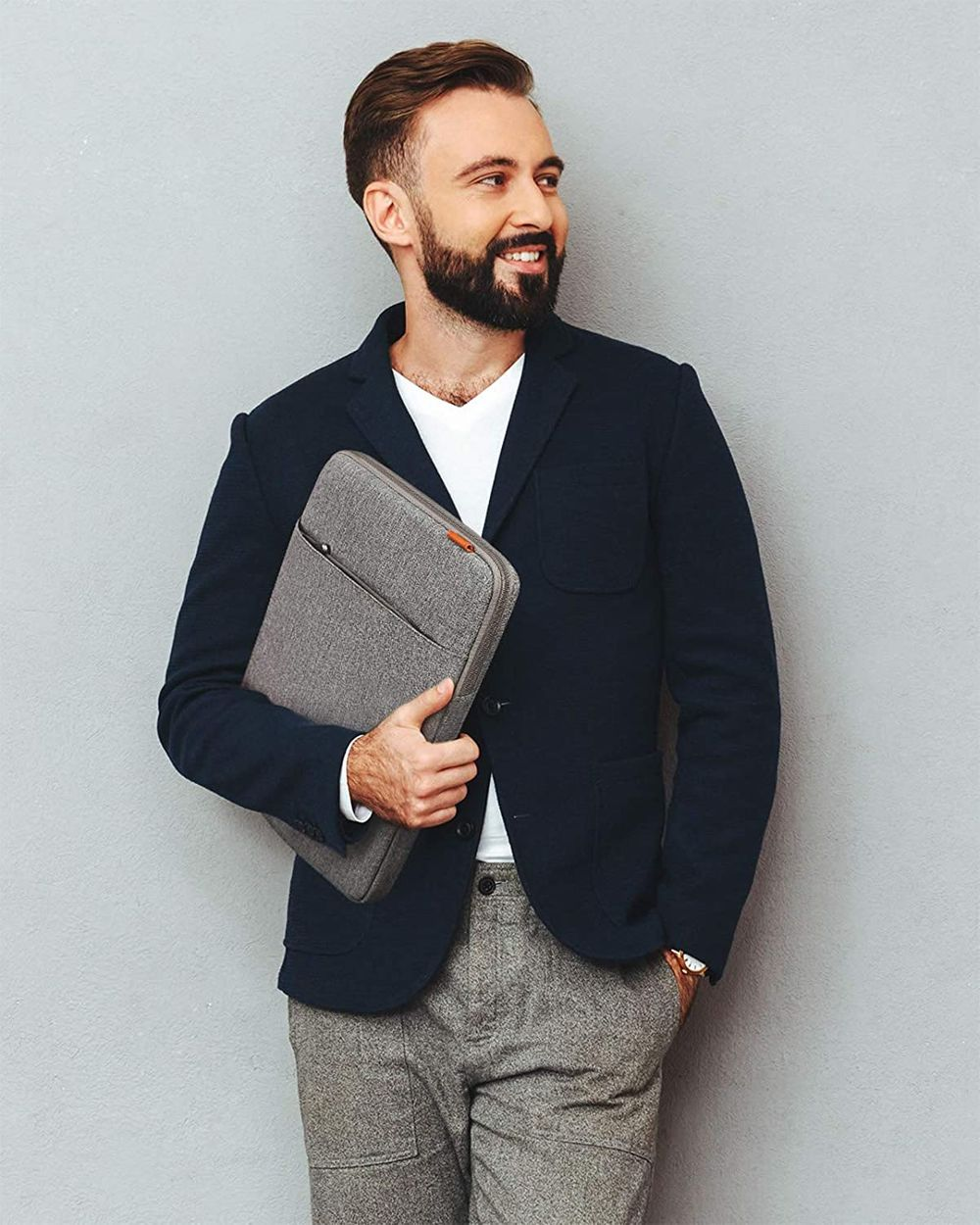 Un hombre con blazer sosteniendo una funda gris para portátil.