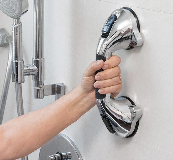 Ein verchromter Haltegriff in einer Dusche, gehalten von einer Hand, für Sicherheit und Unterstützung.
