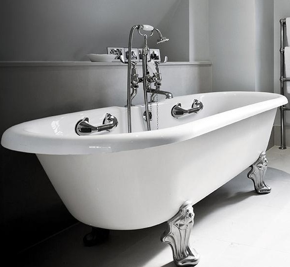 Weiße Badewanne mit Löwenfüßen und Chromarmaturen in einem hellen Badezimmer.
