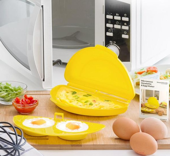 Omeletera amarilla para microondas. Huevos, tomates y cebolletas en una tabla de madera.