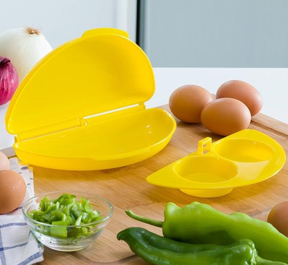 Poachador de huevos amarillo con huevos, pimientos verdes y cebolla en tabla de cortar.