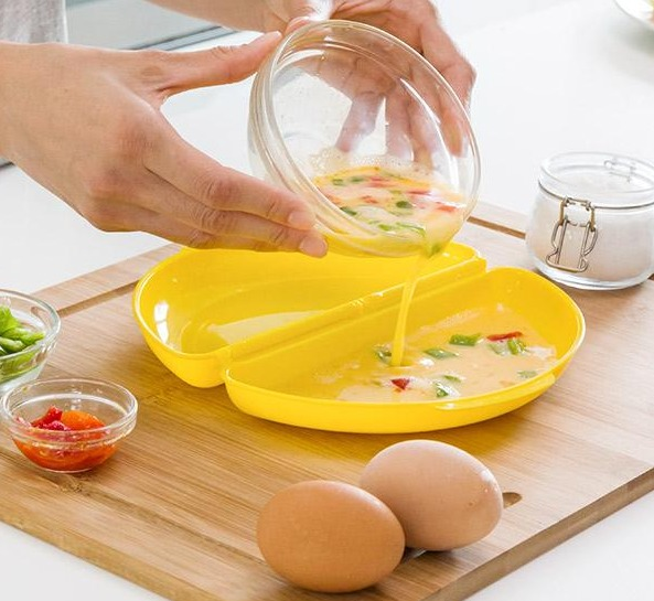 Una persona vierte mezcla de huevo en un plato amarillo dividido sobre una tabla de cortar de madera. Se ven huevos.