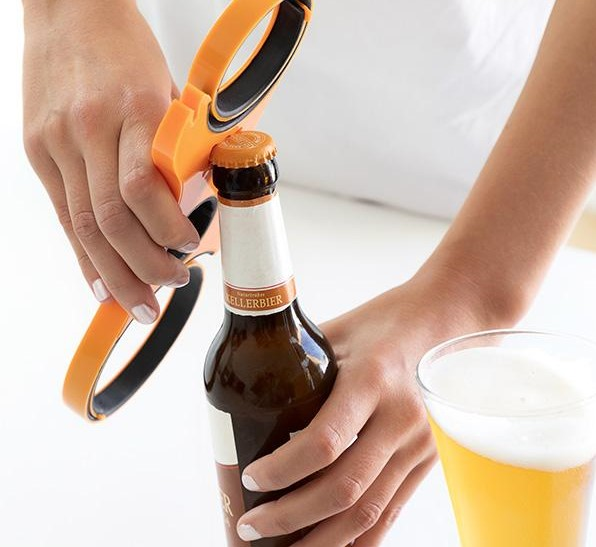Eine Person öffnet eine Bierflasche mit einem orange-schwarzen Flaschenöffner.