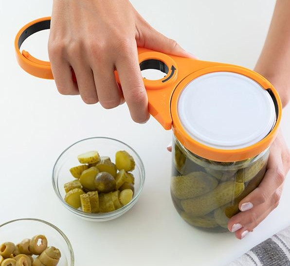 Person benutzt einen orangen Gläseröffner. Ein Glas Gurken und zwei Schüsseln.