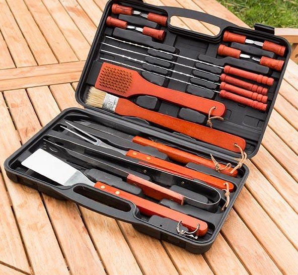 Ein offenes schwarzes Grill-Werkzeugset mit verschiedenen Werkzeugen auf einem Holztisch.