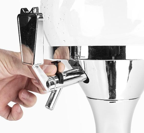 Die Hand einer Person bedient einen silbernen Wasserhahn an einem klaren, zylindrischen Getränkespender.