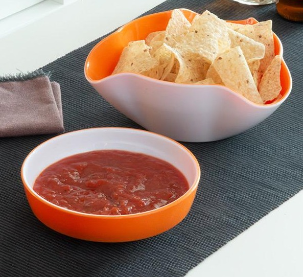 Dos cuencos de comida; uno con totopos y otro con salsa roja sobre una superficie oscura.