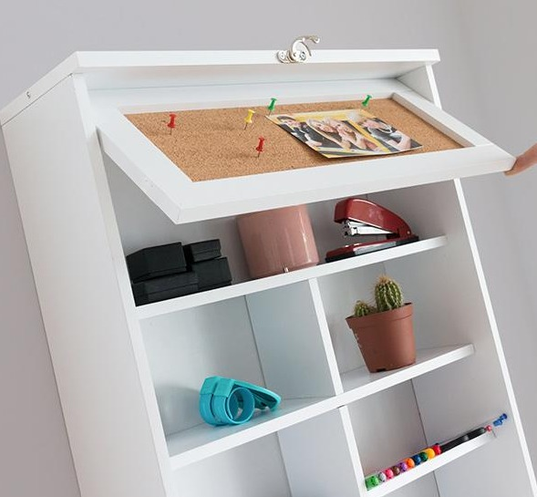 Weißer Schrank mit Pinnwand, Schreibtischzubehör und Dekorationsartikeln.