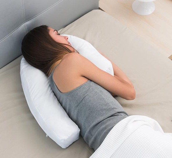 Frau schläft auf einem Bett mit weißem Kissen und weißer Decke.
