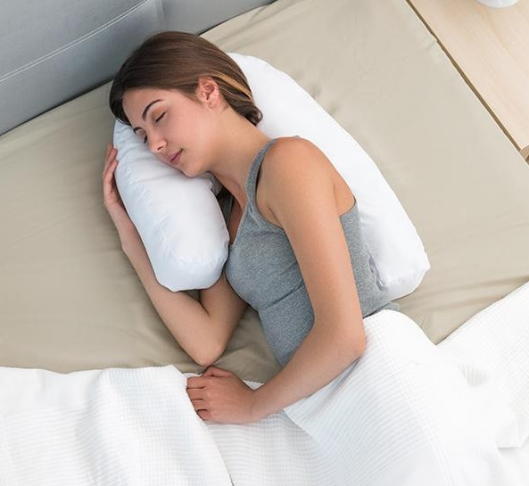 Frau schläft auf einem Bett mit einem weißen Kissen. Weiße Bettwäsche vorhanden.