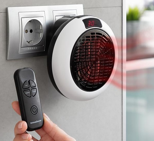 Un riscaldatore bianco e nero collegato a una presa a muro, con un telecomando.