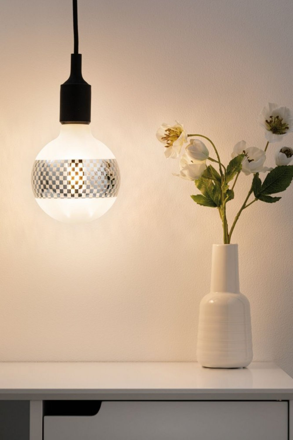Glühbirne mit weißer Vase und Blumen hängen. Weißer Hintergrund.