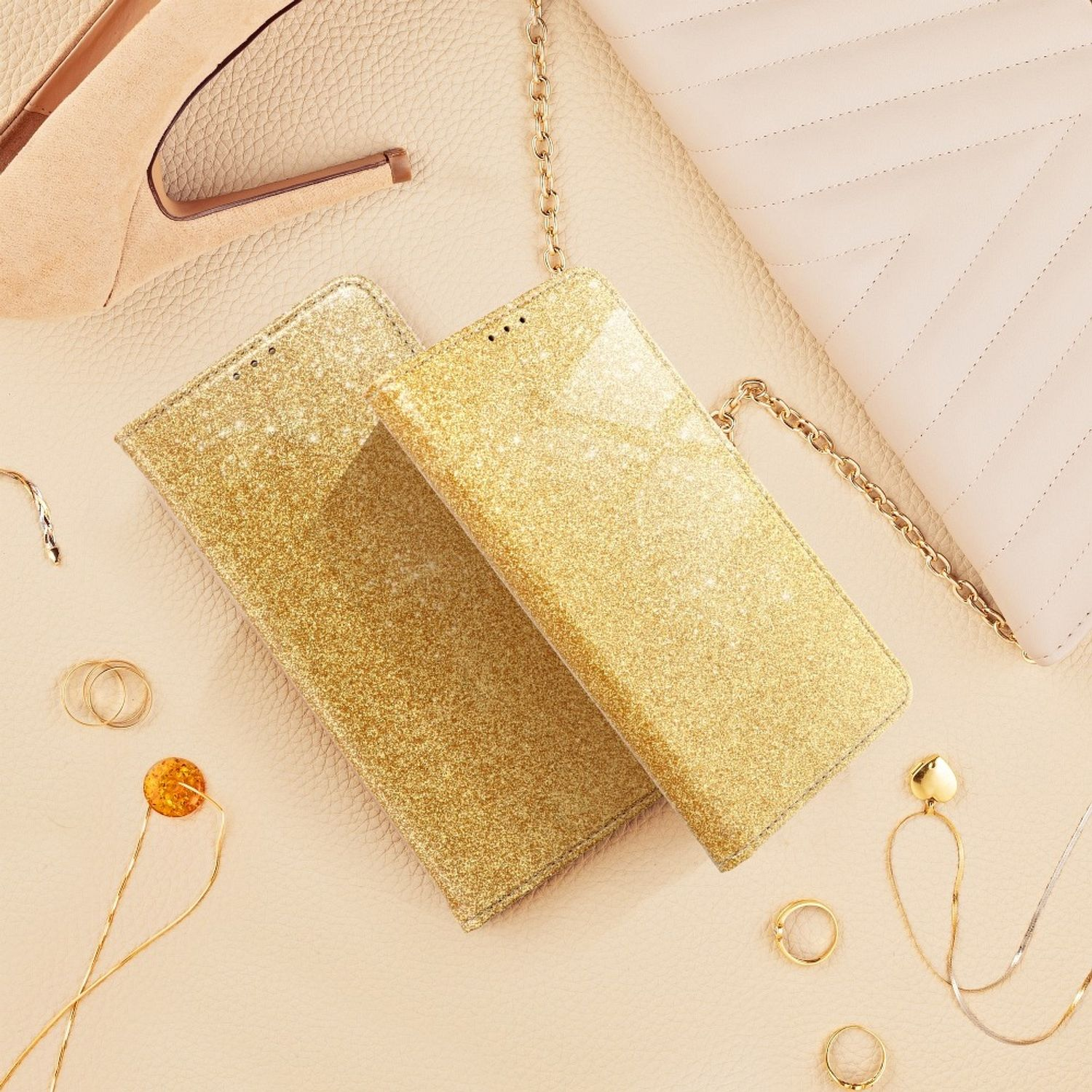 Zwei goldene Glitzer-Handyhüllen und Accessoires auf hellbeigem Untergrund. Draufsicht.