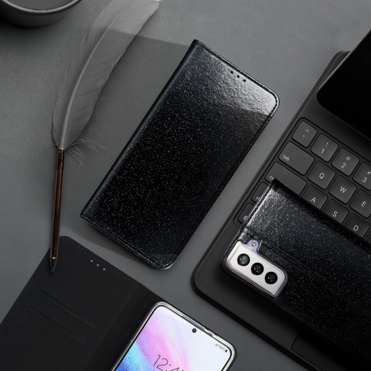Schwarzes Telefonzubehör: Telefon, Hülle, Feder auf grauem Hintergrund und ein Laptop.