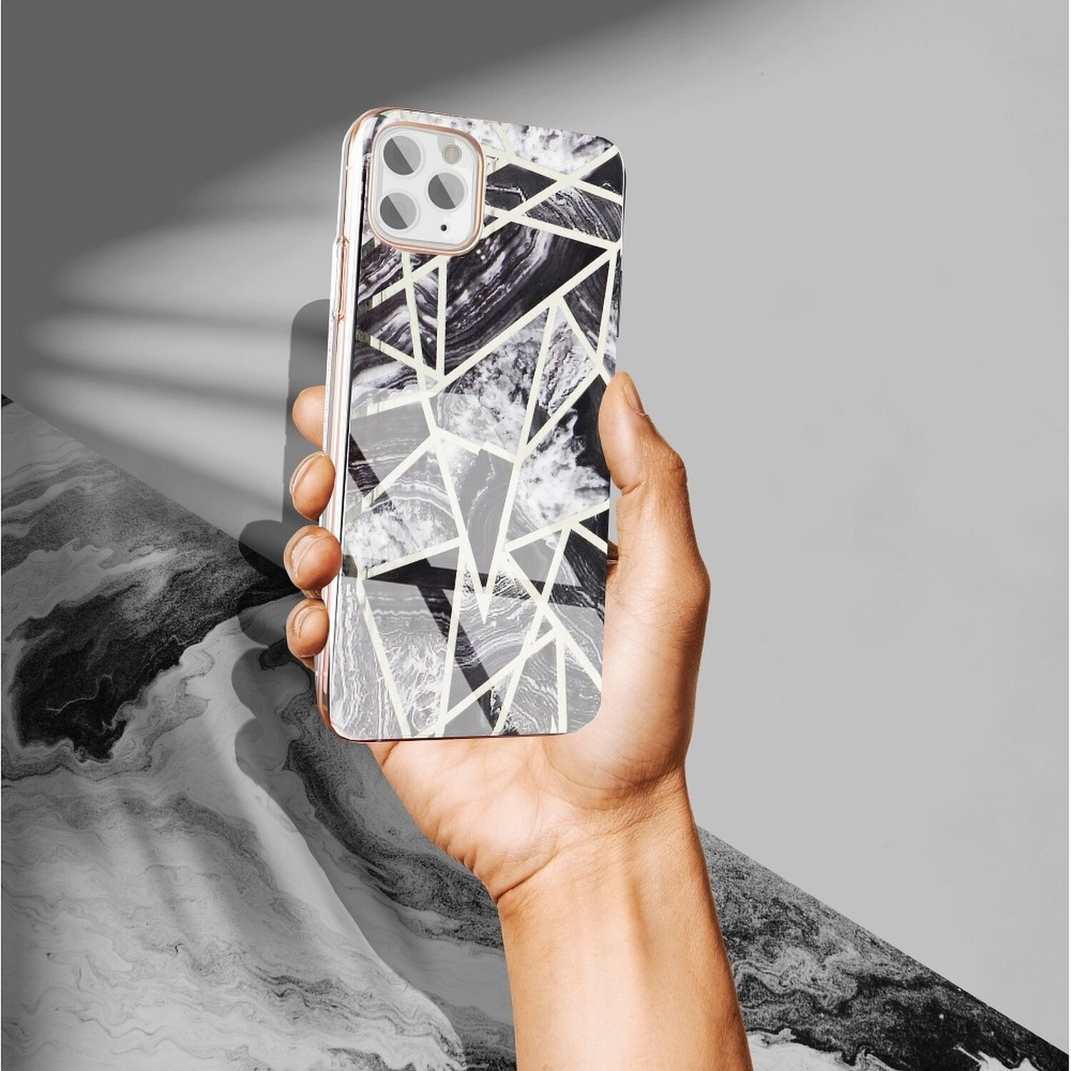 Hand hält ein Telefon mit geometrischer Musterhülle. Die Hülle ist schwarz und weiß.