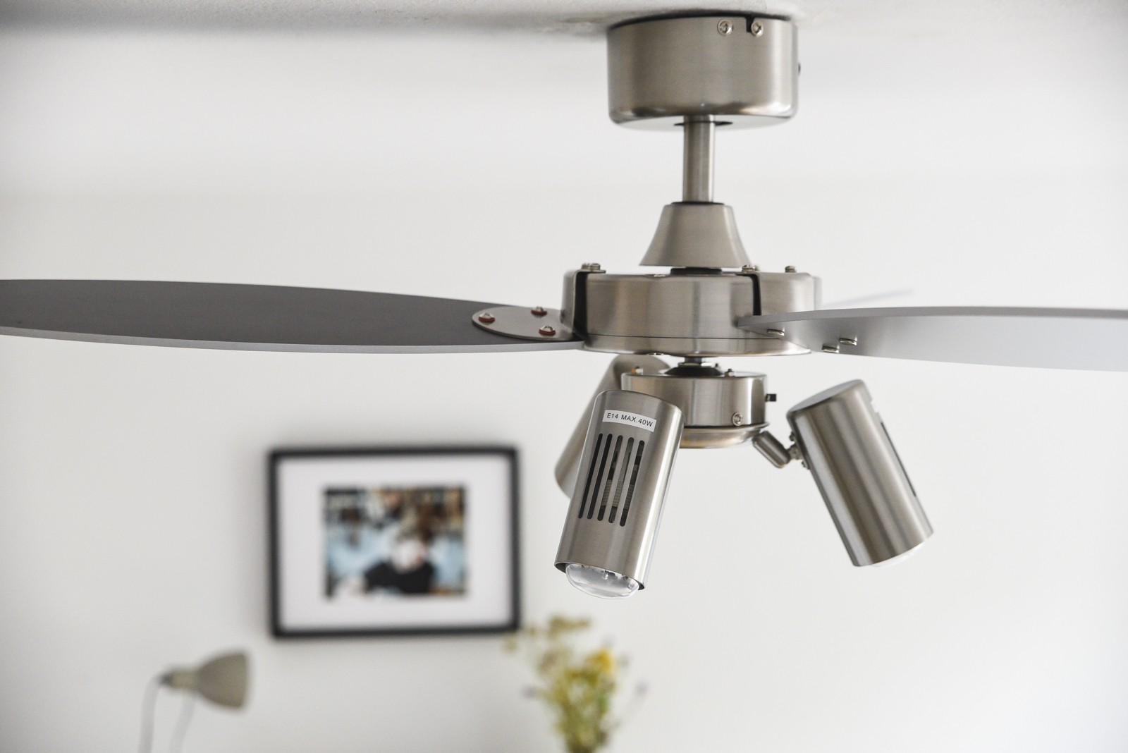 Deckenventilator mit Lichtern, ein Bild und eine Lampe sind im Hintergrund.