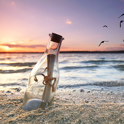 Nachricht in einer Flasche am Sandstrand bei Sonnenuntergang. Vögel fliegen am Himmel.