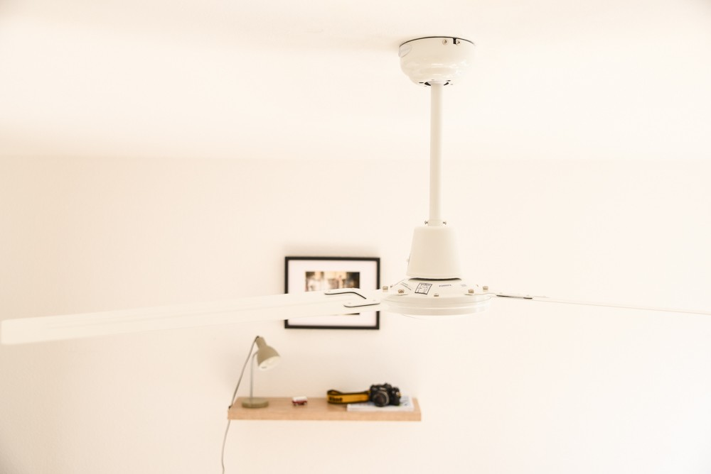 Deckenventilator mit Licht und gerahmtem Bild an der Wand. Kleiner Schreibtisch darunter.