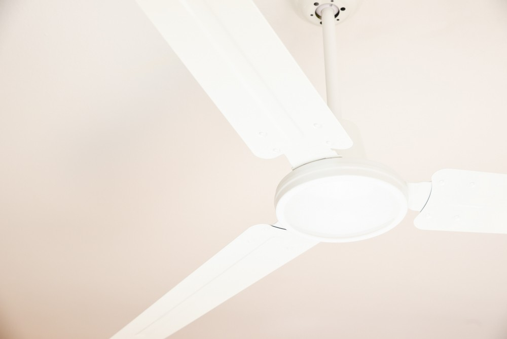 Weißer Deckenventilator mit drei Flügeln, an einer weißen Decke.