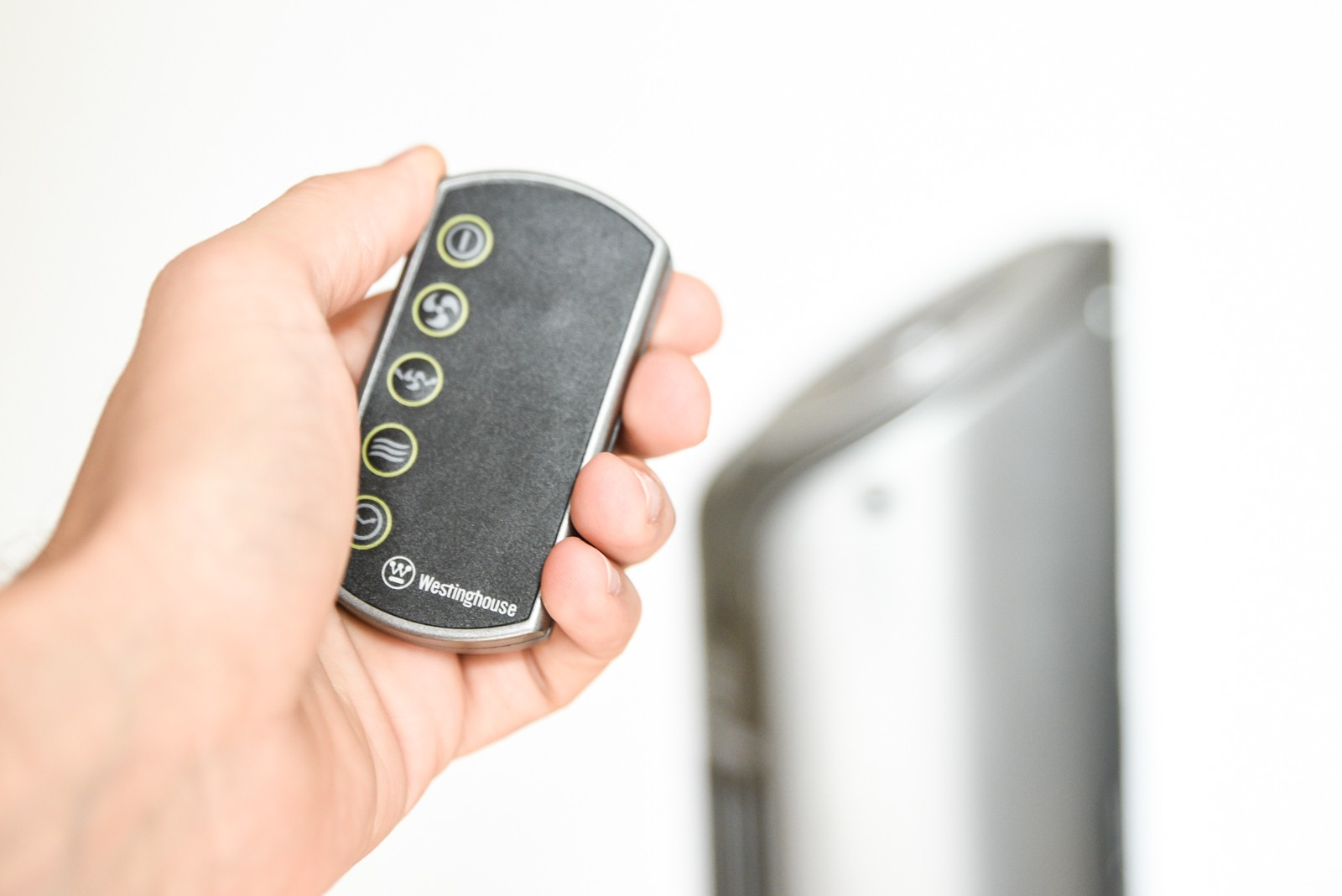 Ręka trzymająca pilota Westinghouse. Tło to biała ściana i wentylator.
