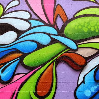 Ein farbenfrohes Graffiti-Wandbild mit blauer, grüner, rosa und brauner Farbe.