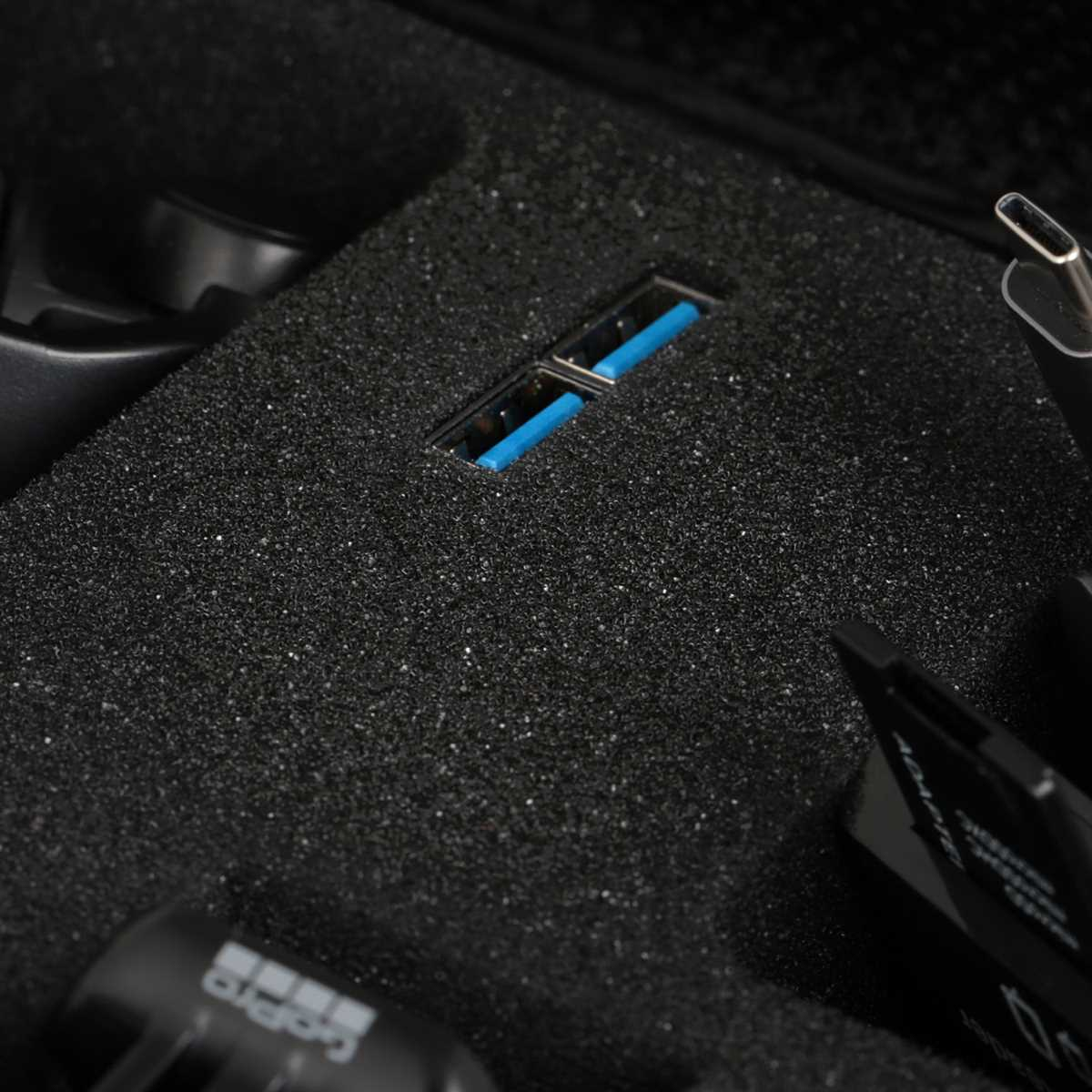 Schwarzer Schaumstoff-Kofferraum mit blauem USB-Anschluss und Zubehör.