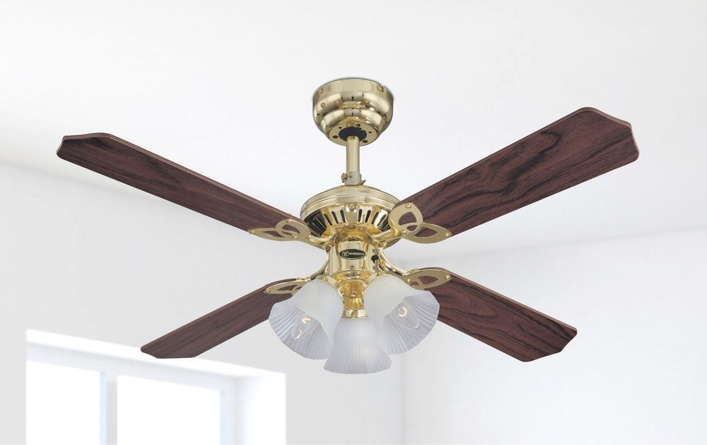 Un ventilatore da soffitto in ottone e legno con quattro pale e tre luci è appeso.