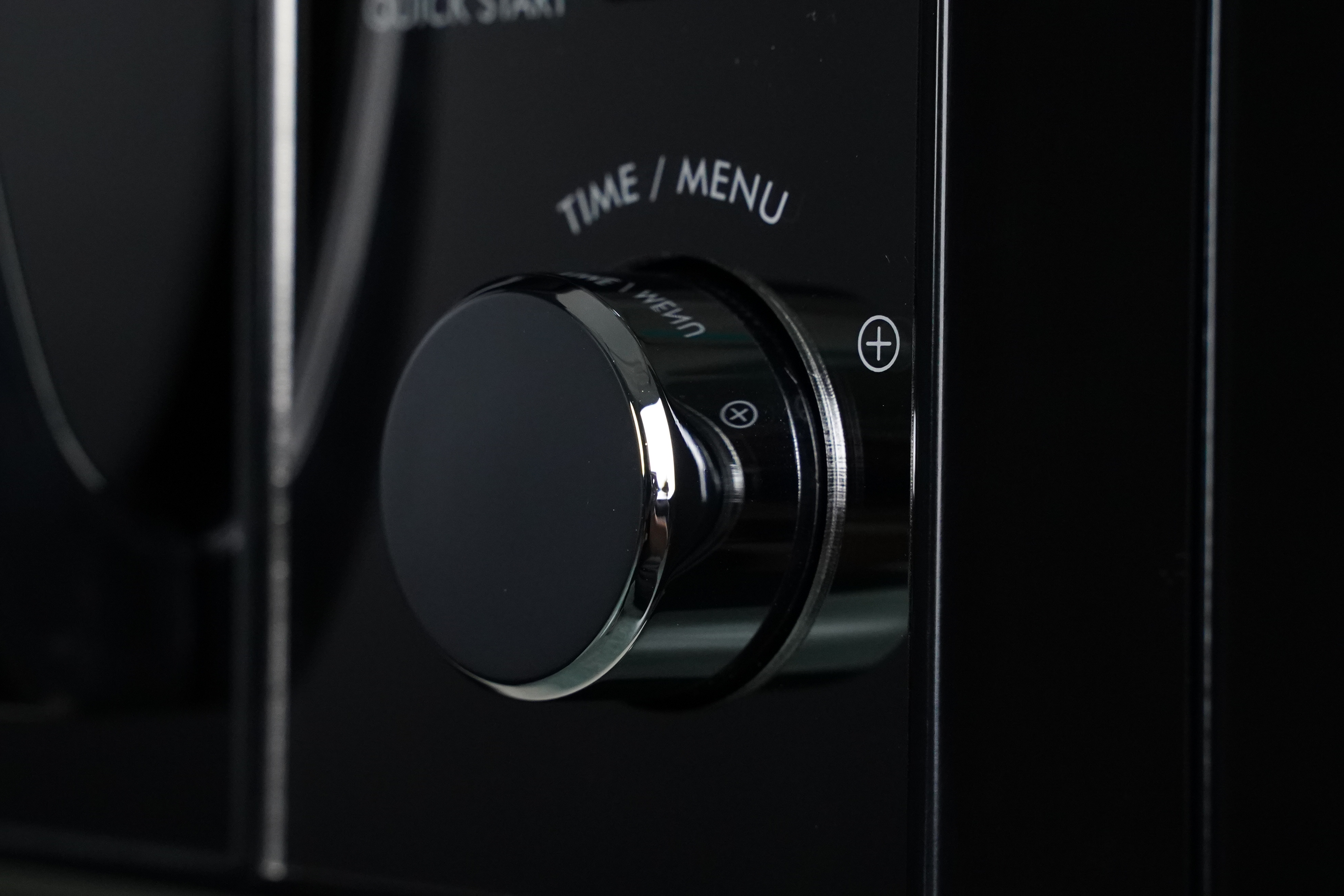 Black microwave control panel with a round dial and time/menu labels.