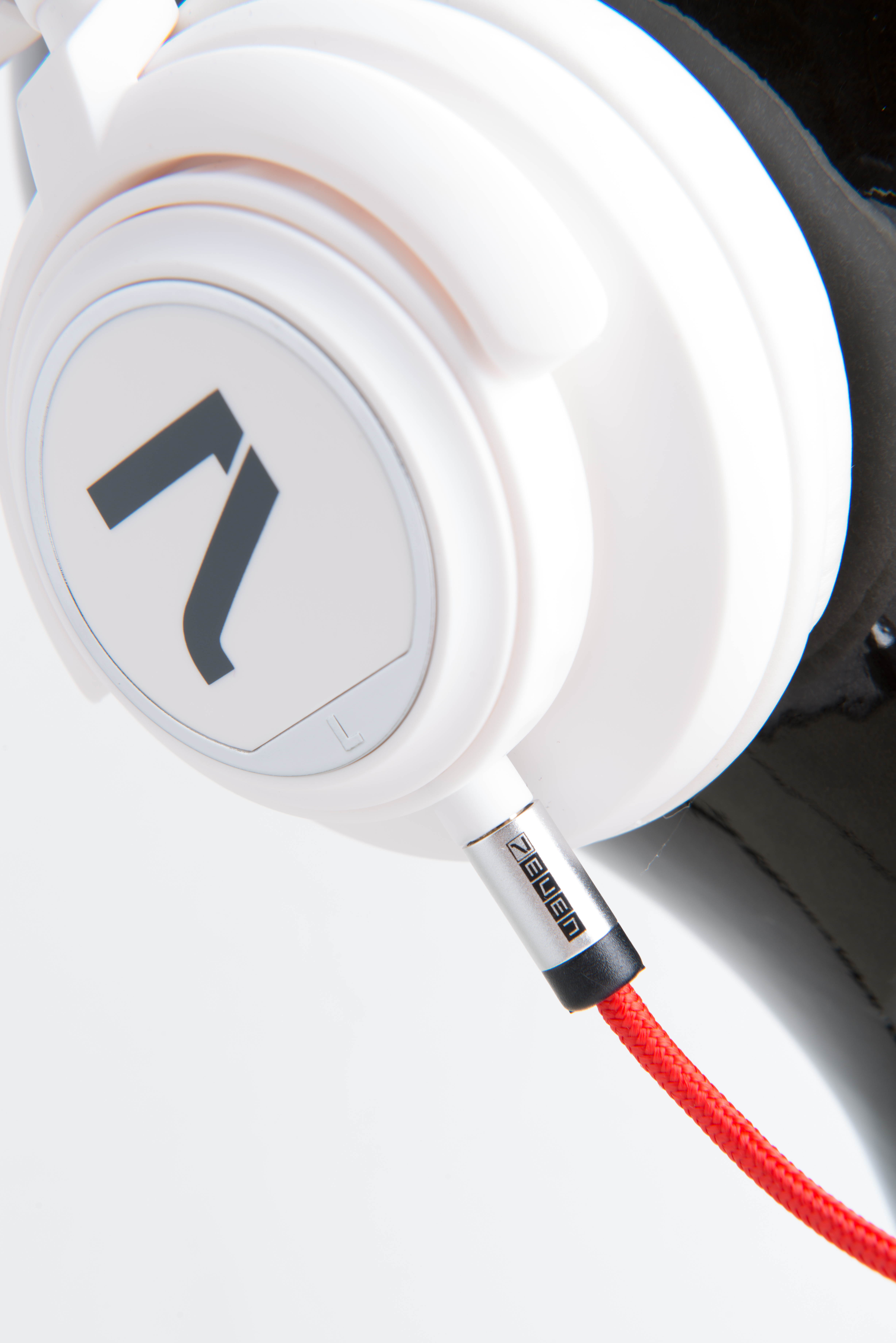 Weiße Kopfhörer mit Logo, rotem Kabel und weißem Hintergrund. Das Kabel ist angeschlossen.