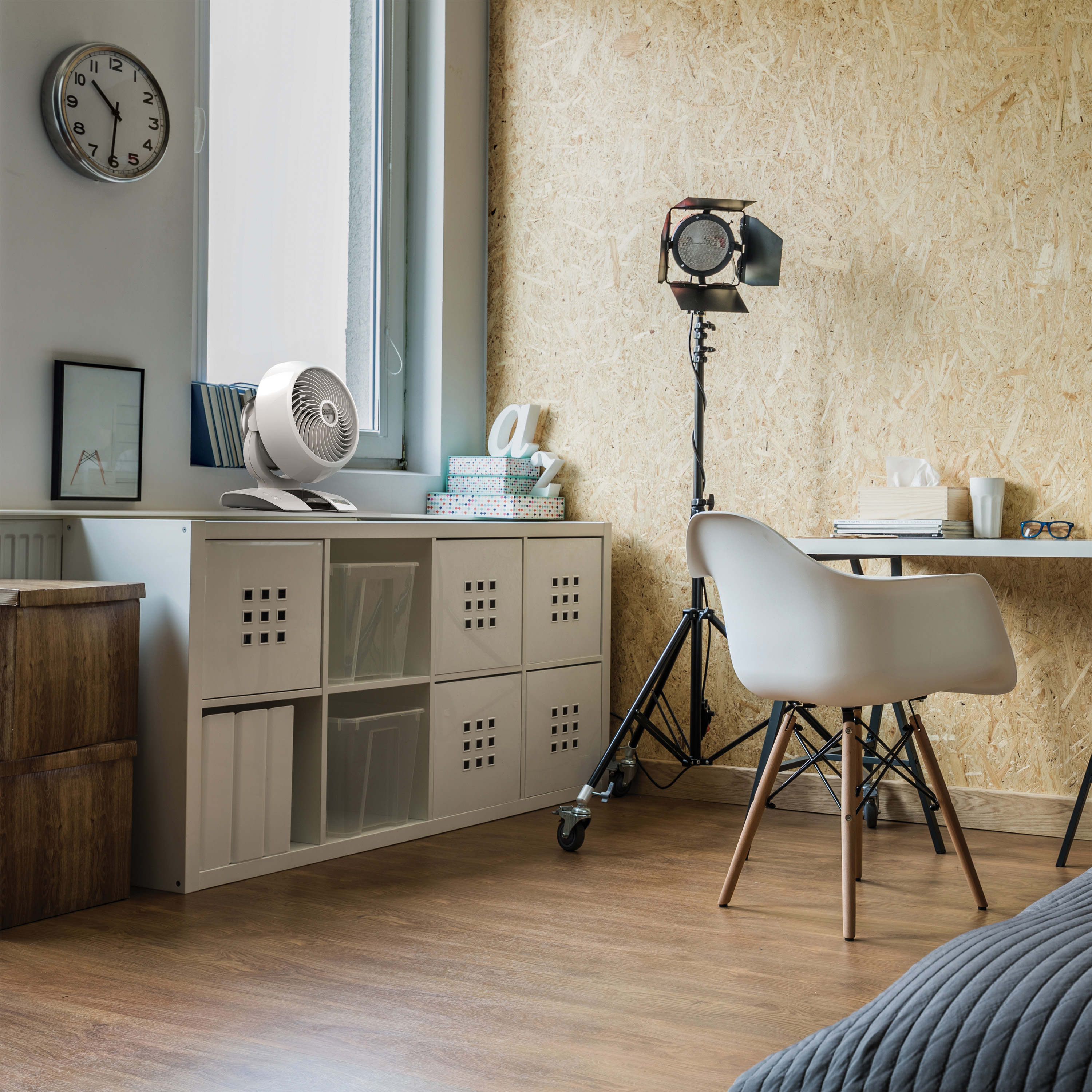 Wnętrze biura z wentylatorem, zegarem i biurkiem.