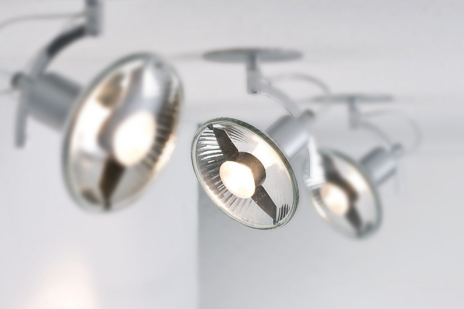 Zbliżenie na trzy srebrne reflektory, ustawione pod kątem od góry, z jasnymi światłami.