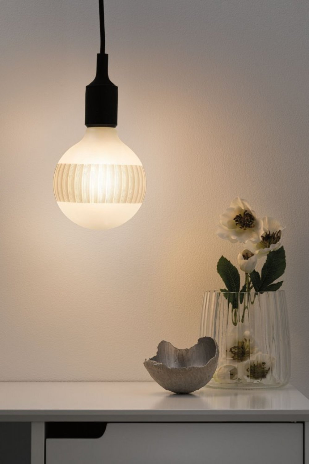 Eine Glühbirne mit weißem Licht und eine Blumenvase.
