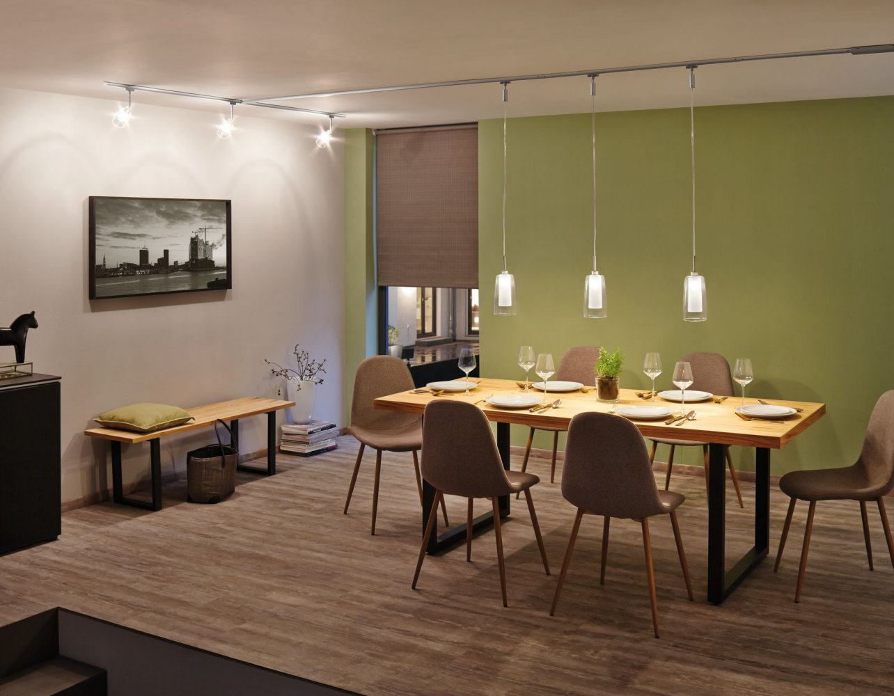 Jadalnia ze stołem drewnianym, krzesłami, oświetleniem szynowym i widokiem z okna.