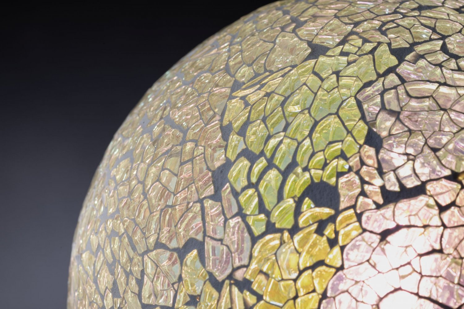 Zbliżenie szklanego przedmiotu z wzorem przypominającym mozaikę w kolorach żółtym i czarnym.