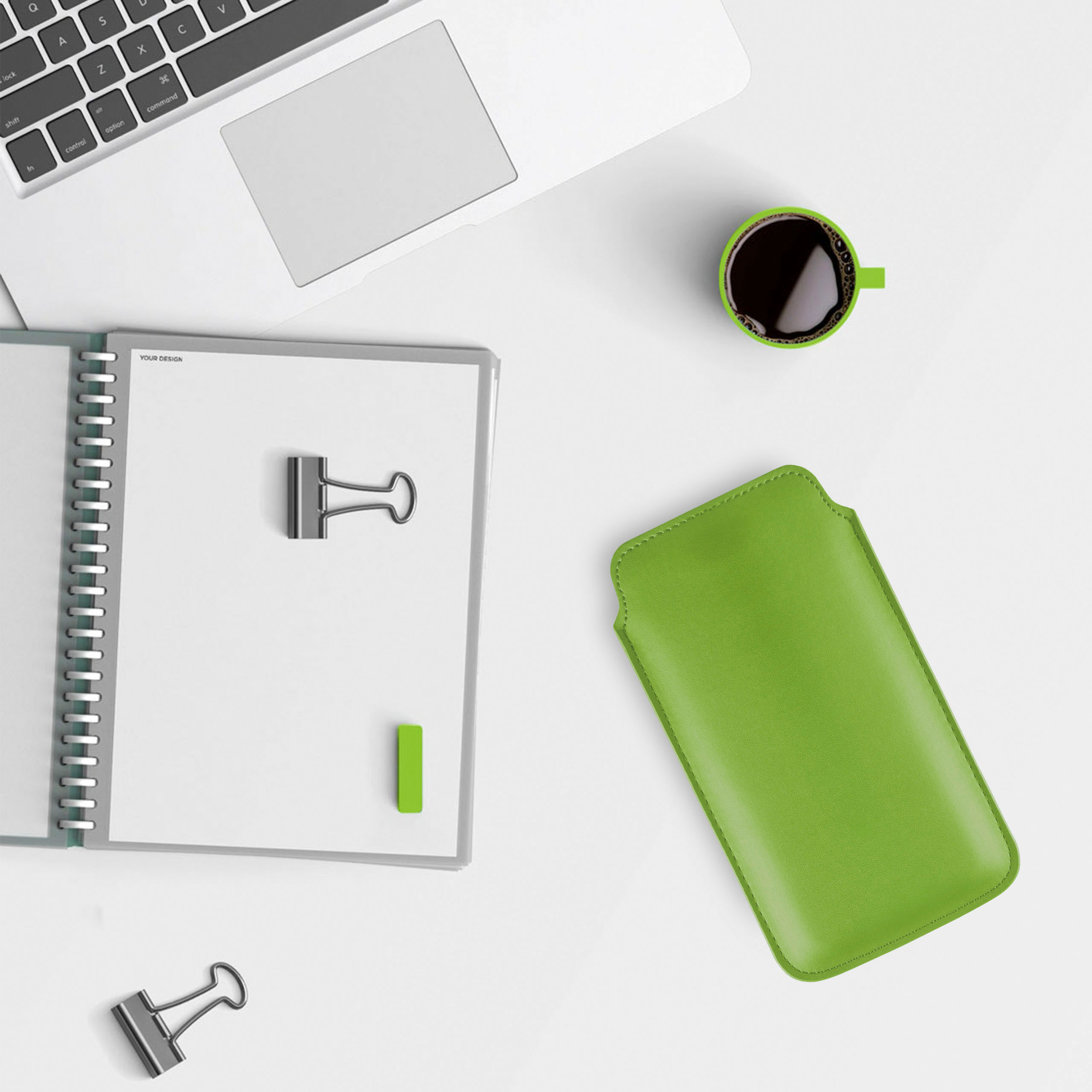 Ein Arbeitsplatz mit Laptop, Notizbuch, grünem Etui und Kaffee.
