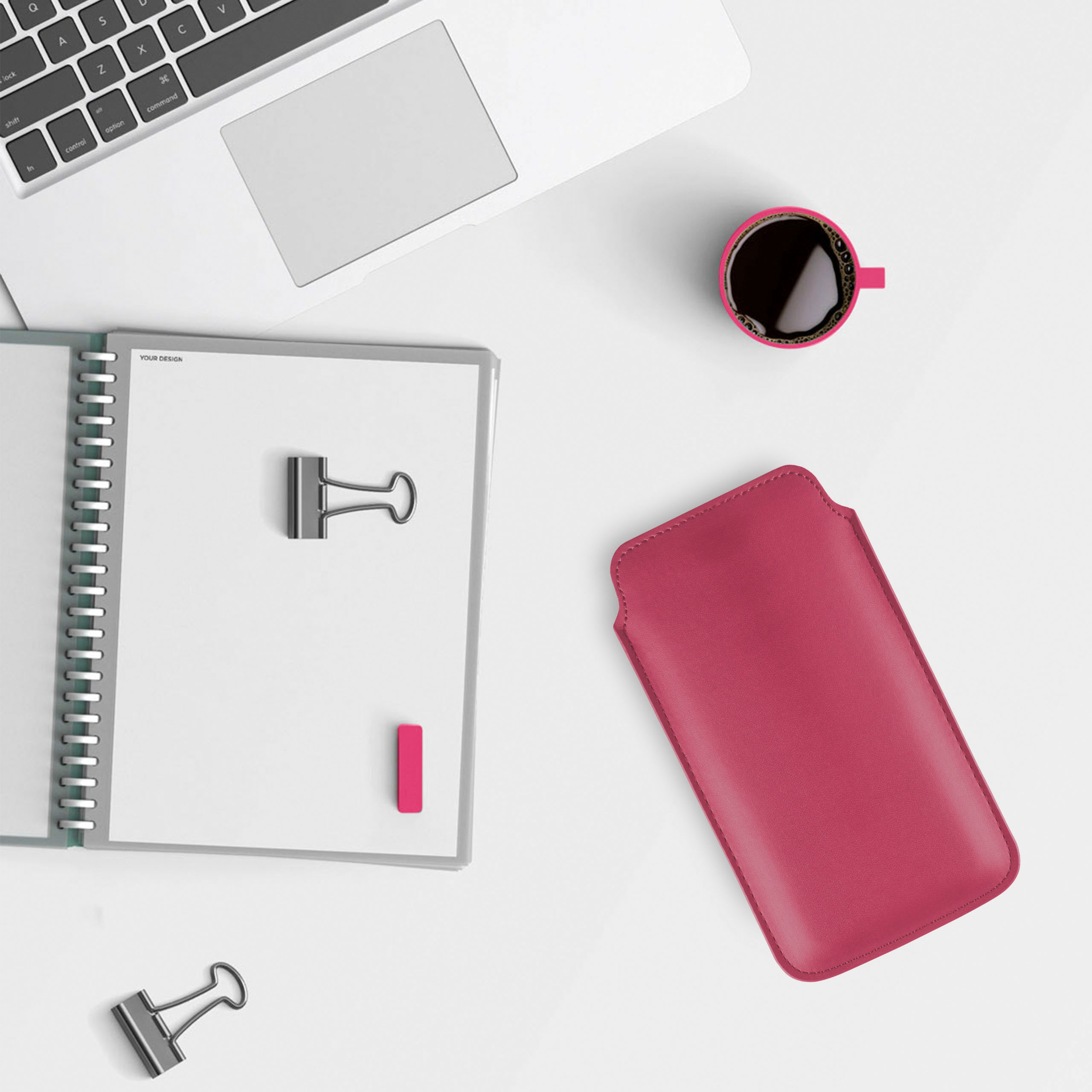 Schreibtisch mit Laptop, Notizbuch, roter Handyhülle, Kaffeetasse und Büroklammern.