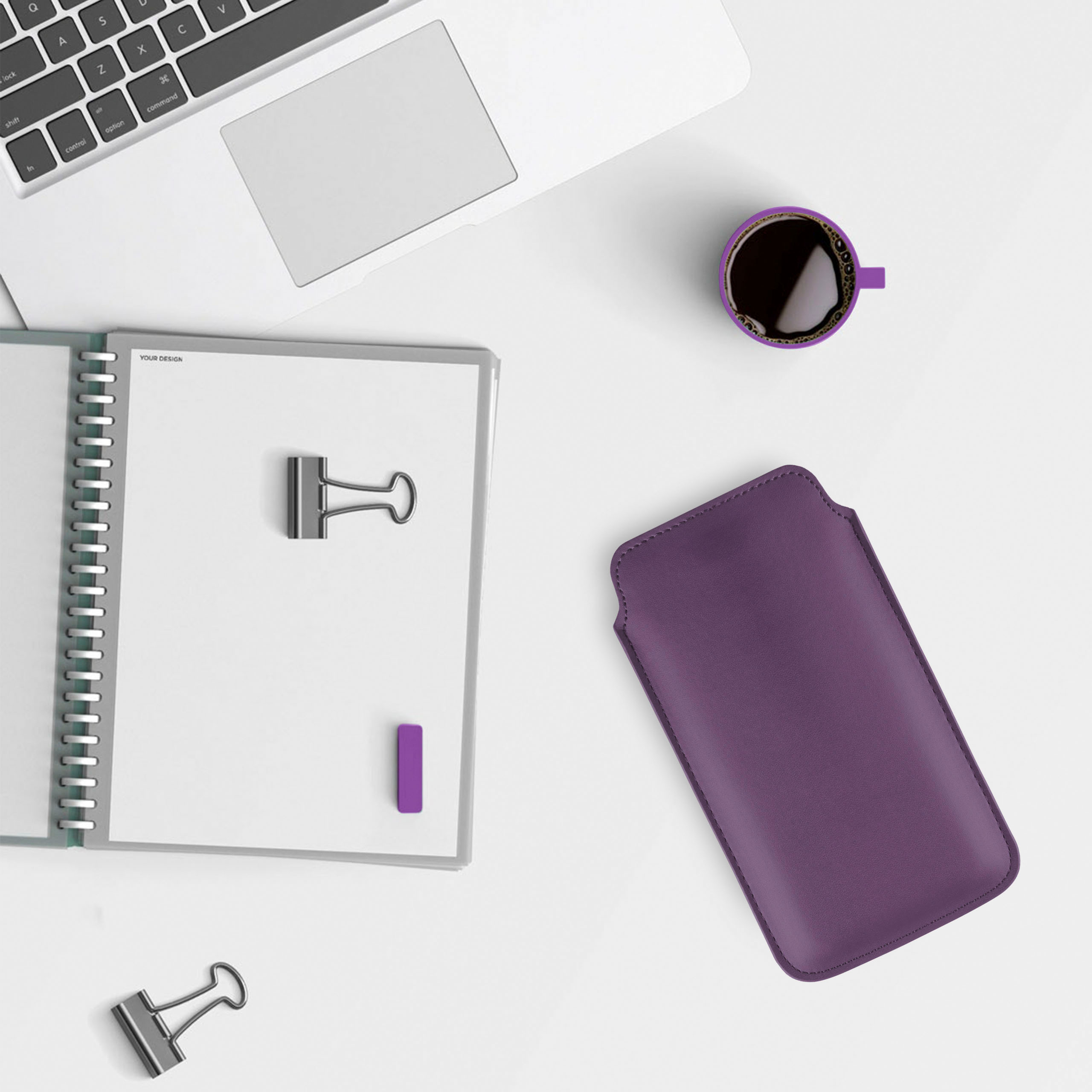 Schreibtisch-Setup mit Laptop, Notizbuch, Stifthalter, Kaffeetasse und lila Hülle.