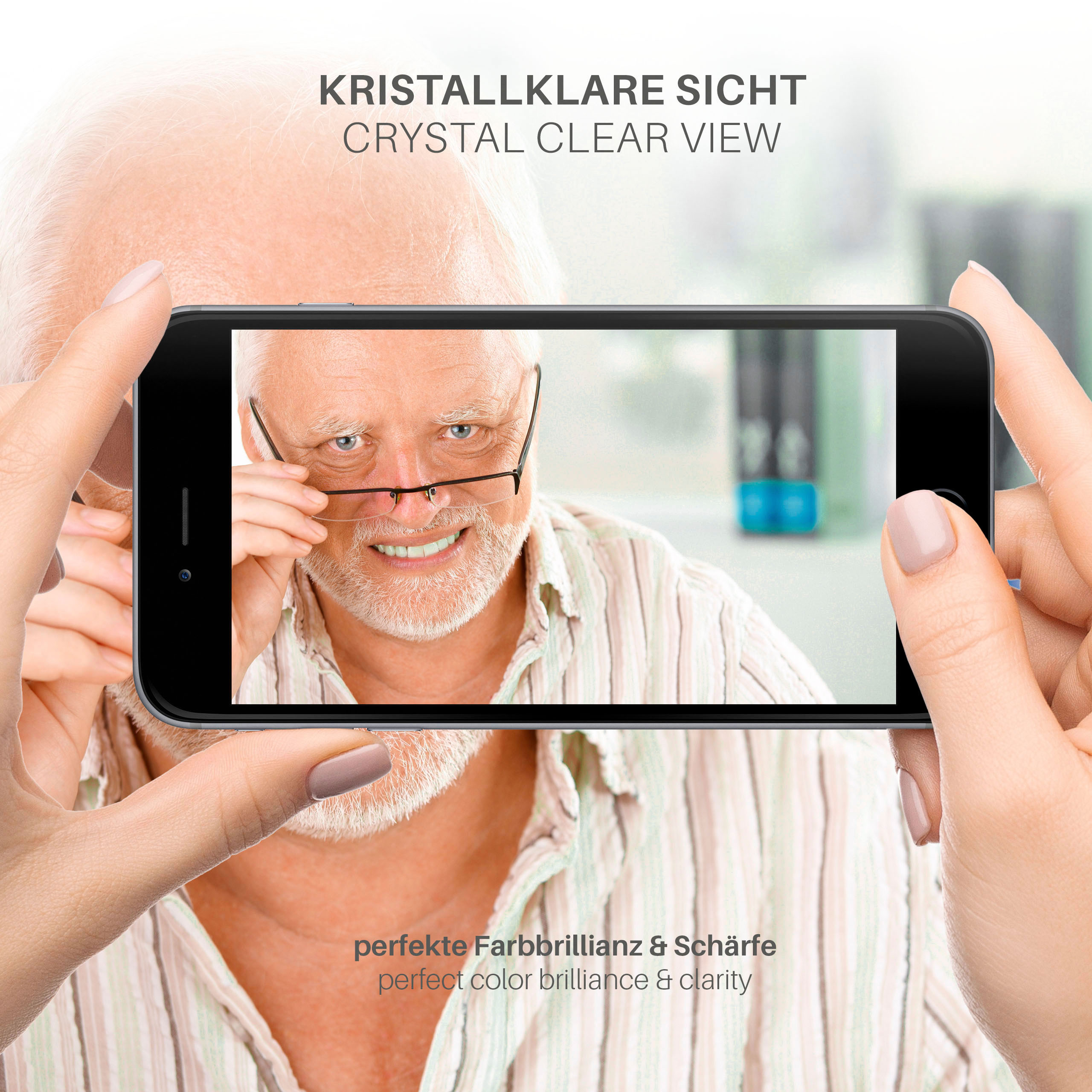 Eine Person hält ein Telefon, das das Gesicht eines älteren Mannes zeigt. Das Bild ist klar.