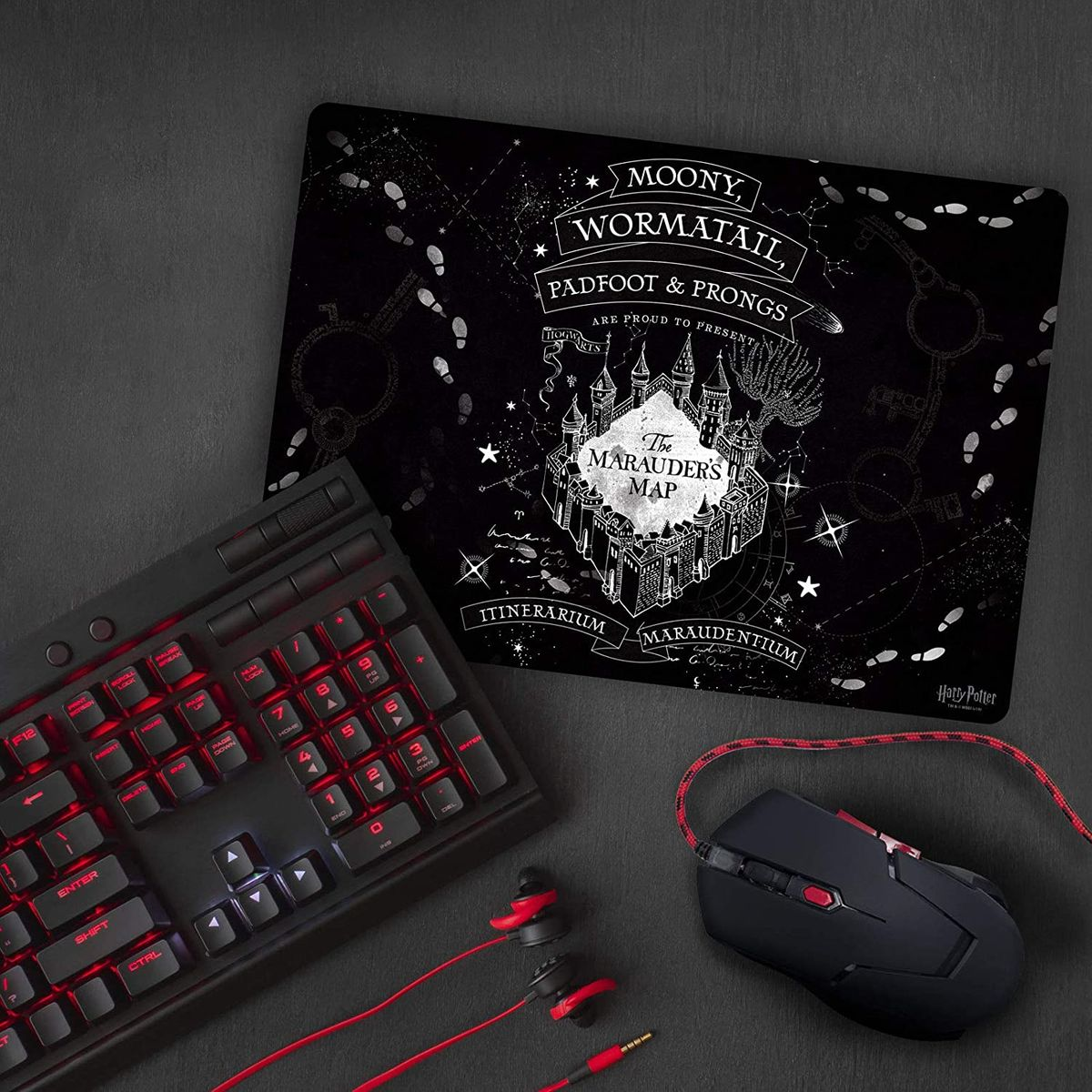 Un clavier, une souris et un casque noirs sur un tapis noir. Le tapis présente un motif de carte.
