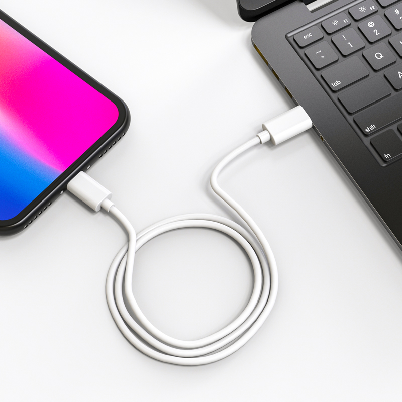 Telefon mit weißem Ladekabel an Laptop angeschlossen.